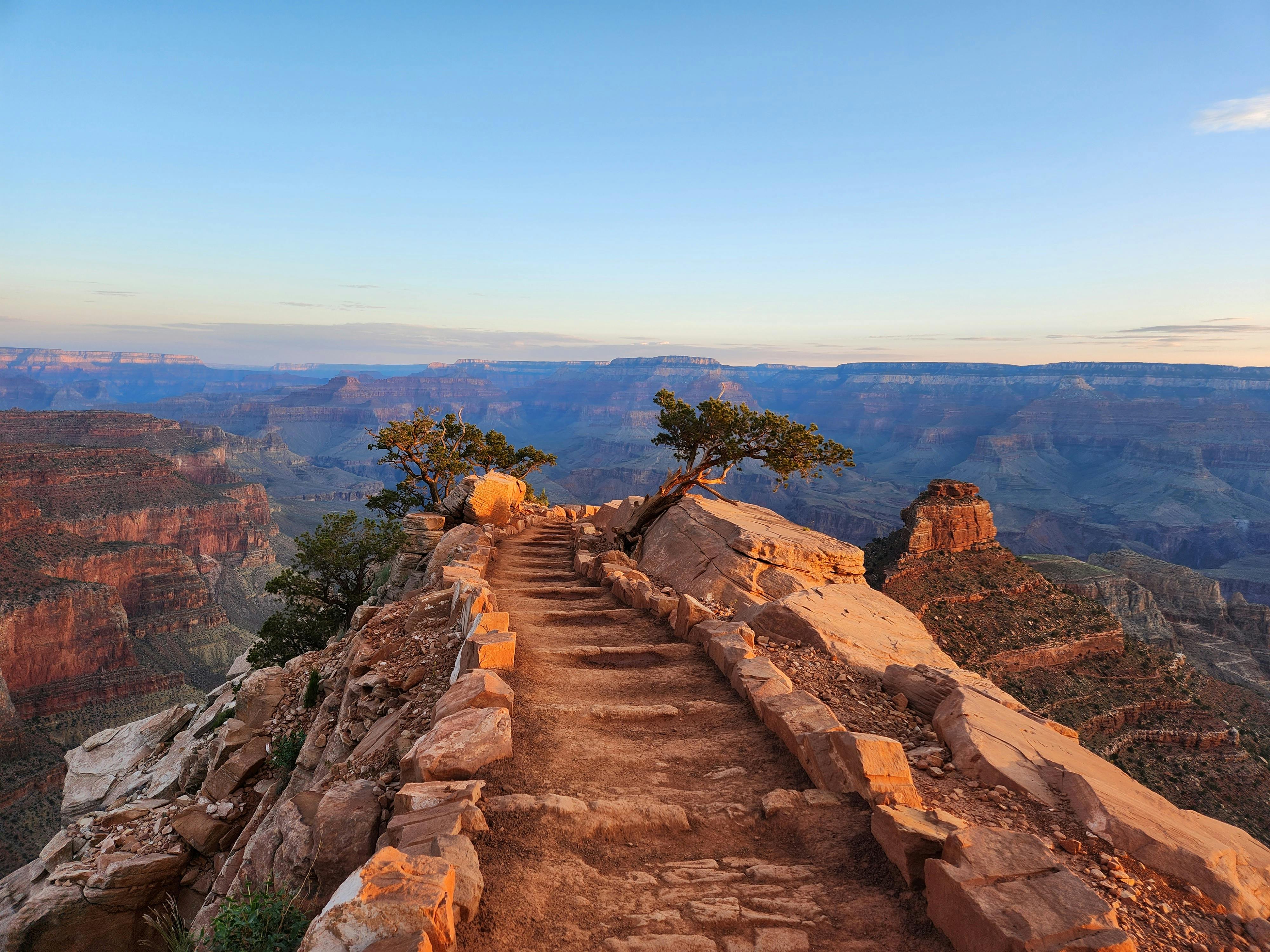 Breathtaking view of a rocky path along the Grand Canyon with clear skies and vast landscapes.