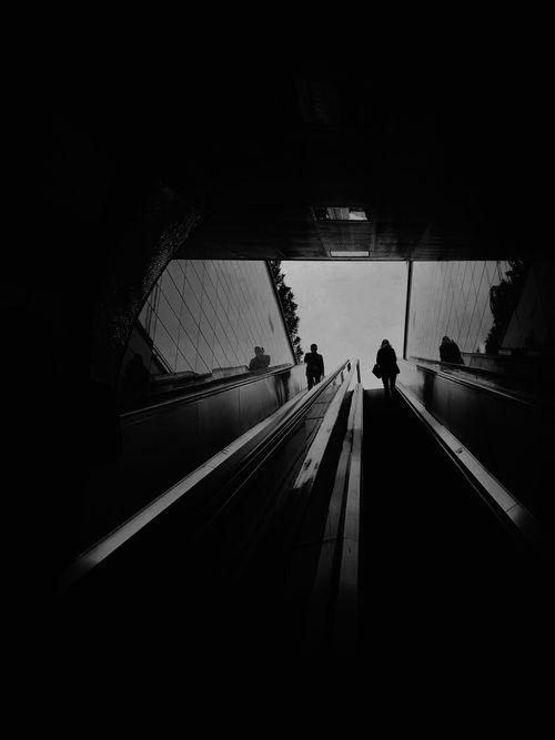 Free Black and white photo capturing silhouettes on an escalator in an urban setting. Stock Photo