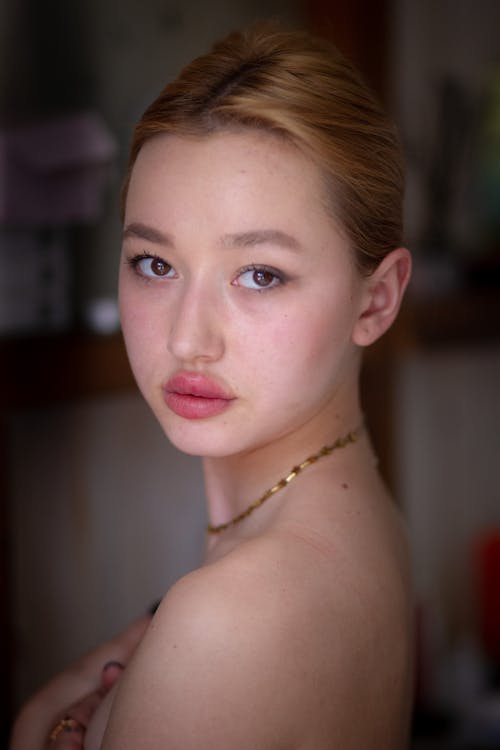 A young woman with a gold necklace and a pink lip