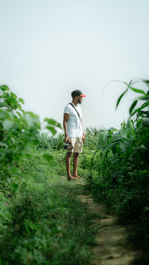 Man in a T-Shirt and Shorts Standing on the Footpath 