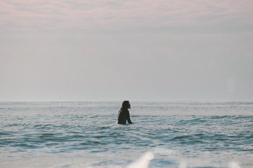 Free A woman enjoys a peaceful swim in the ocean at sunrise. Perfect for vacation and relaxation themes. Stock Photo