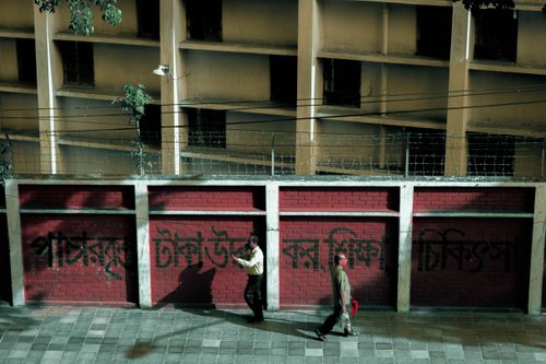 Free Two adults walking by a graffiti-covered wall in Dhaka, Bangladesh. Stock Photo