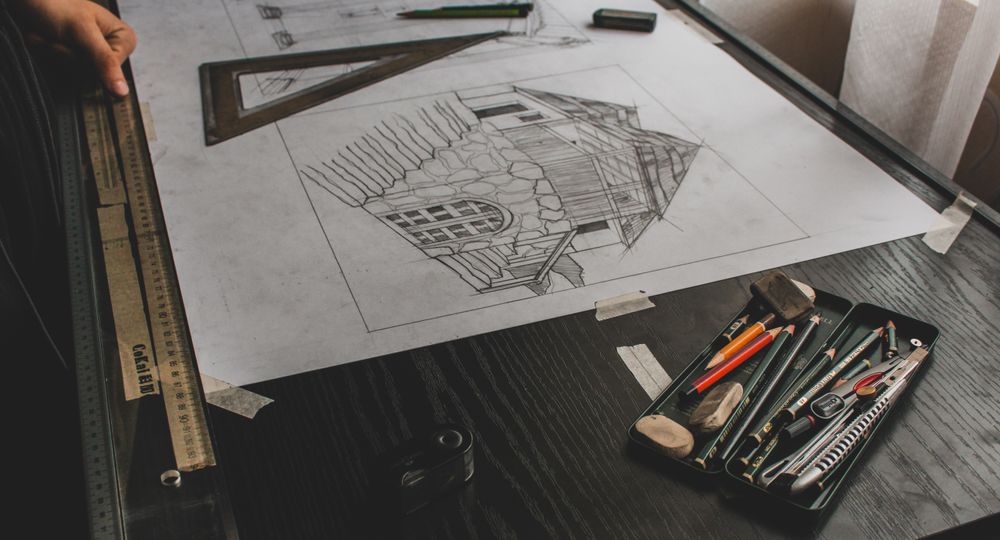 A hand-drawn garden plan on a desk with pencils and a ruler