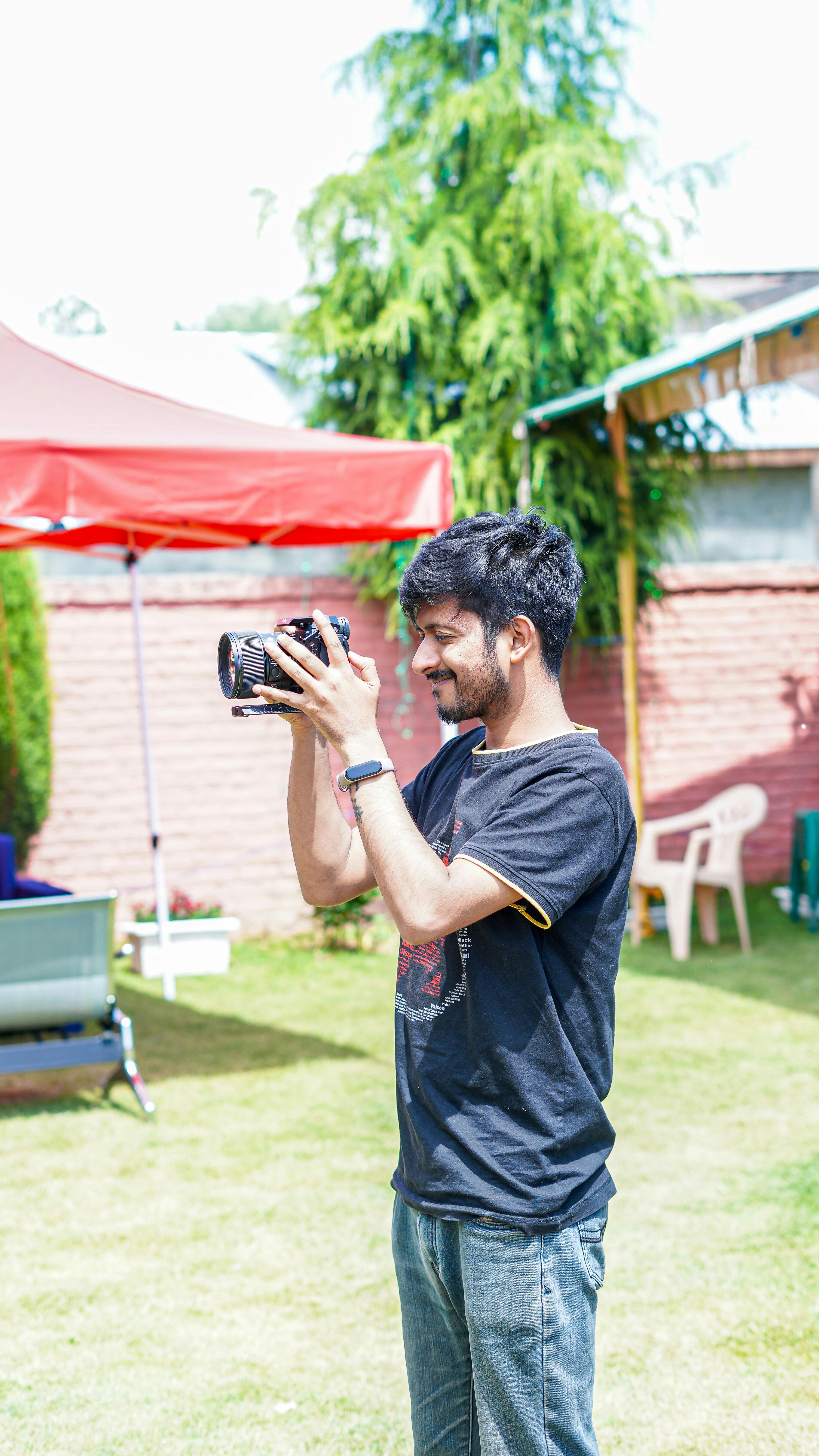 Young man taking photos in a vibrant garden setting, showcasing outdoor photography.