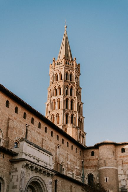 A beautiful view of a historic basilica tower in Toulouse, France, at sunset.