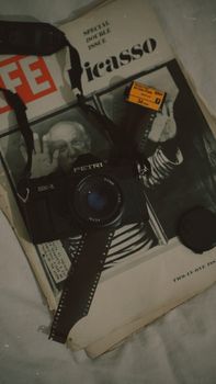 Close-up of a vintage Petri camera on a Life magazine, alongside a film strip and cover.