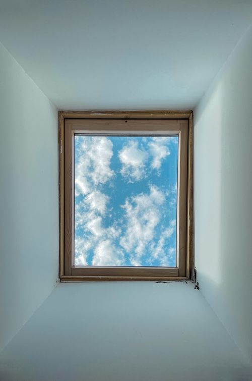 Free A skylight window showing a clear blue sky with fluffy clouds, photographed indoors in Lisbon, Portugal. Stock Photo