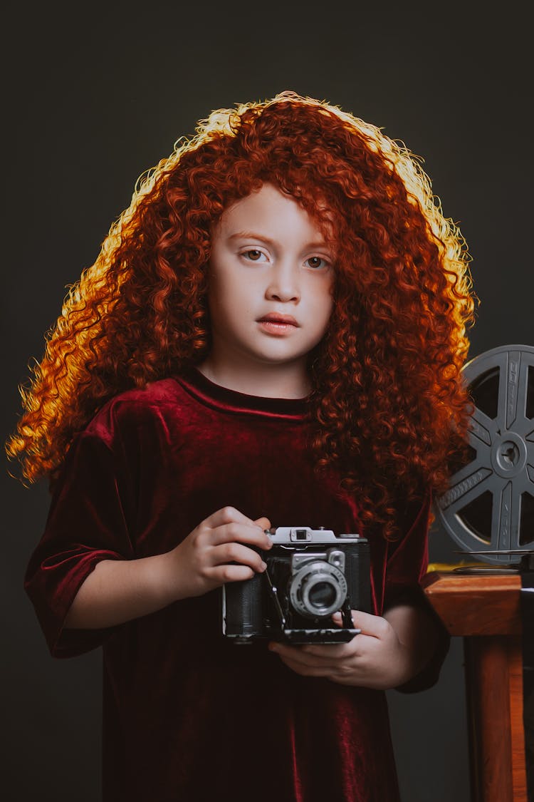 A Red Haired Girl Holding A Vintage Camera