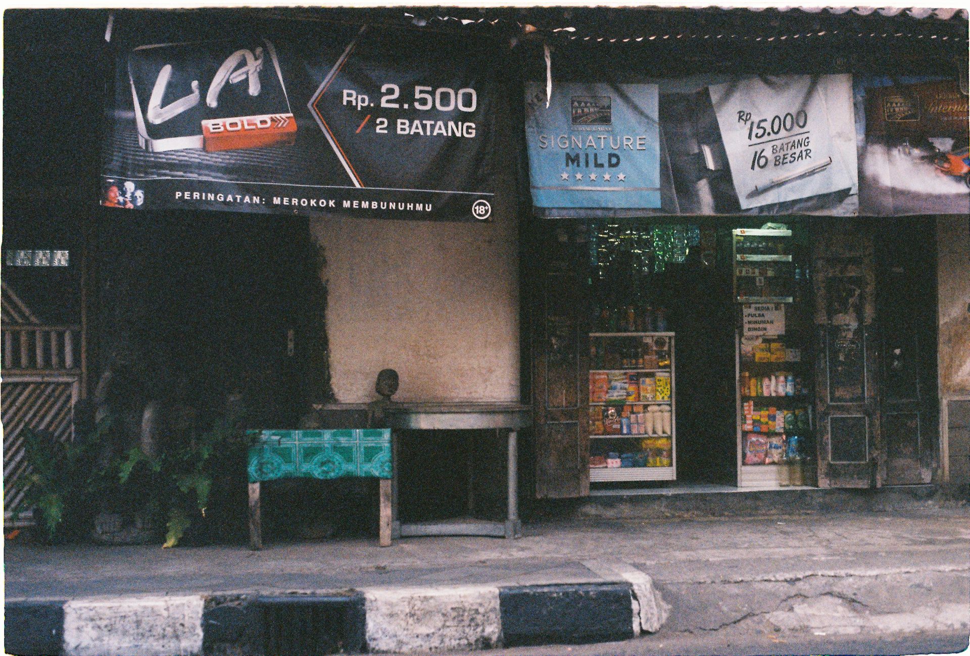 A small street-side shop with cigarette advertisements in Yogyakarta, Indonesia.