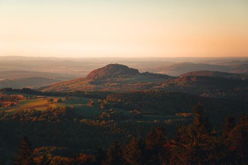 Free Breathtaking aerial view of hills and fields bathed in sunset glow, creating a serene landscape. Stock Photo