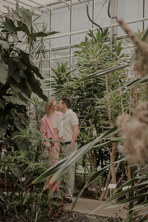 Man and Woman Kissing among Plants in Greenhouse