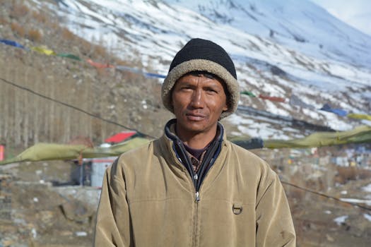 A man in warm clothing stands in snowy mountainous Lahul, India.