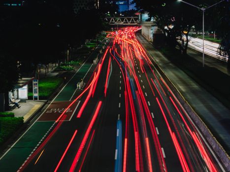Long exposure photo capturing colorful light trails on a busy urban street at night.