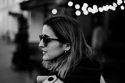 Free Black and white portrait of a woman wearing sunglasses in profile view with blurry lights. Stock Photo
