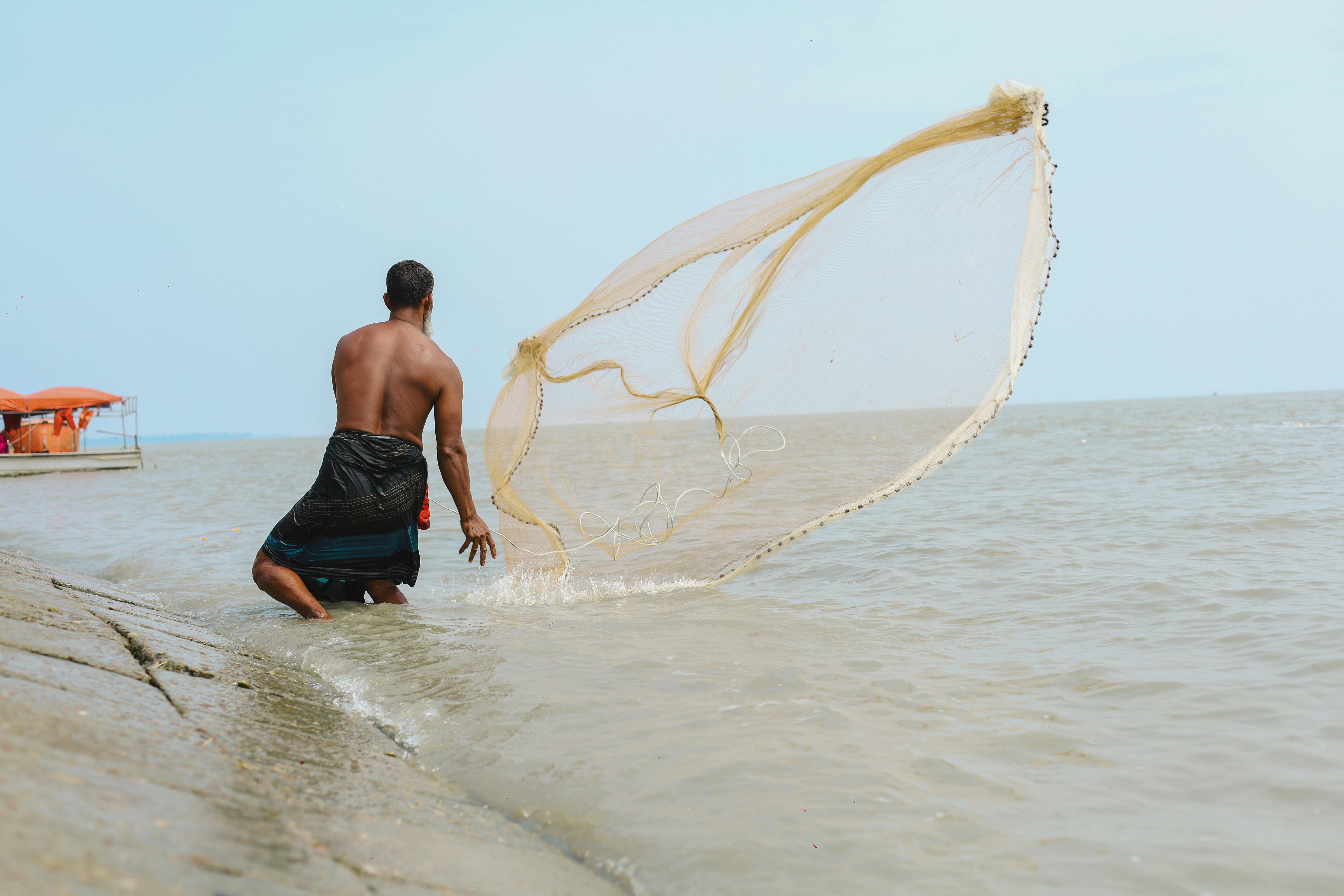 Person throwing white fish net on body of water photo – Free