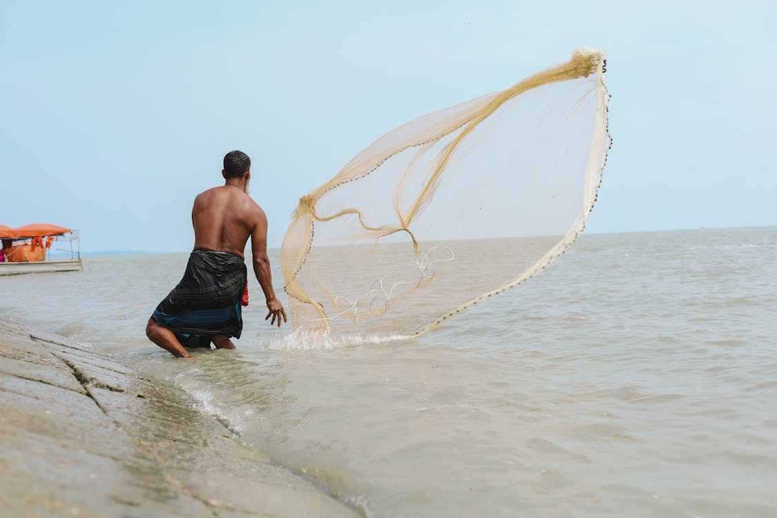Man Throwing Fishing Net into Sea · Free Stock Photo