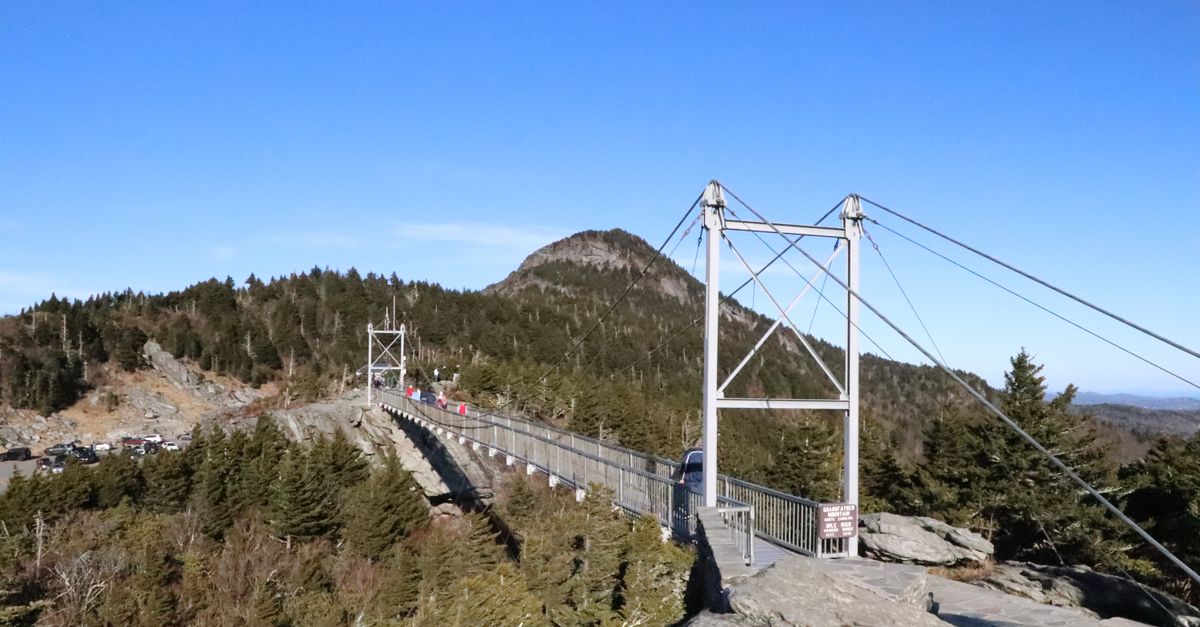 A breathtaking view of the bridge at Grandfather Mountain, NC amid lush pine trees.
