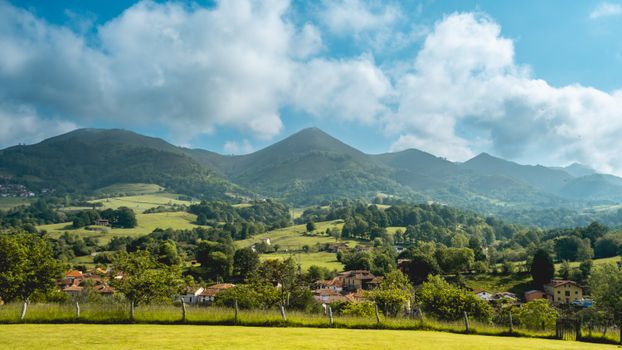 Explore the lush rural landscapes and mountain views of Covadonga, Spain, under a vibrant summer sky.