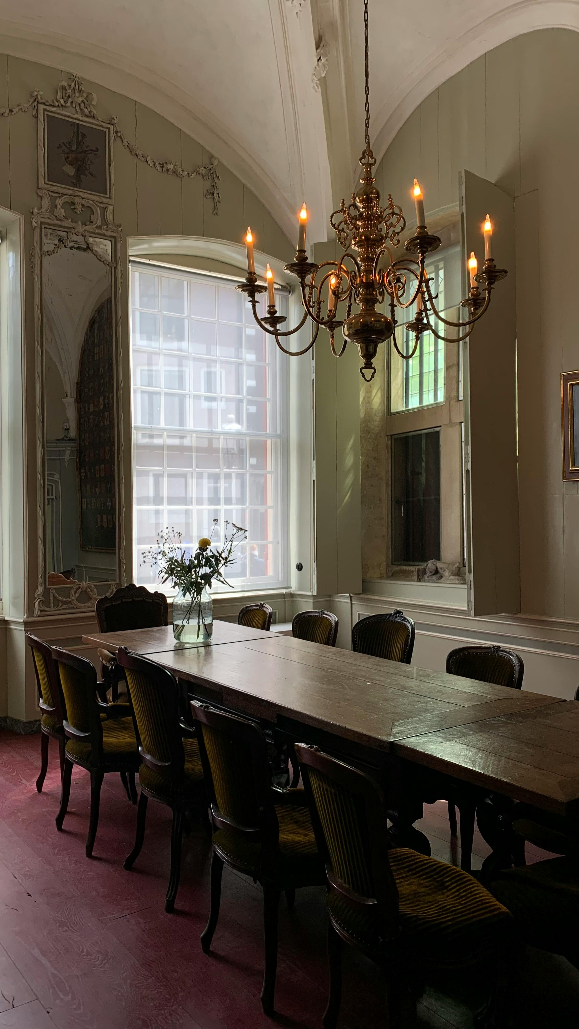 Ornate dining room with a long table and chandelier, perfect for formal gatherings.