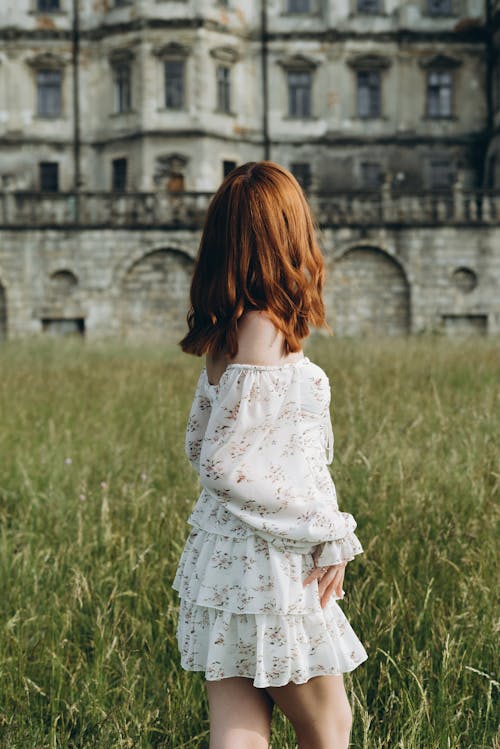 Redhead Woman in Mini Sundress with Floral Print in Meadow by Castle