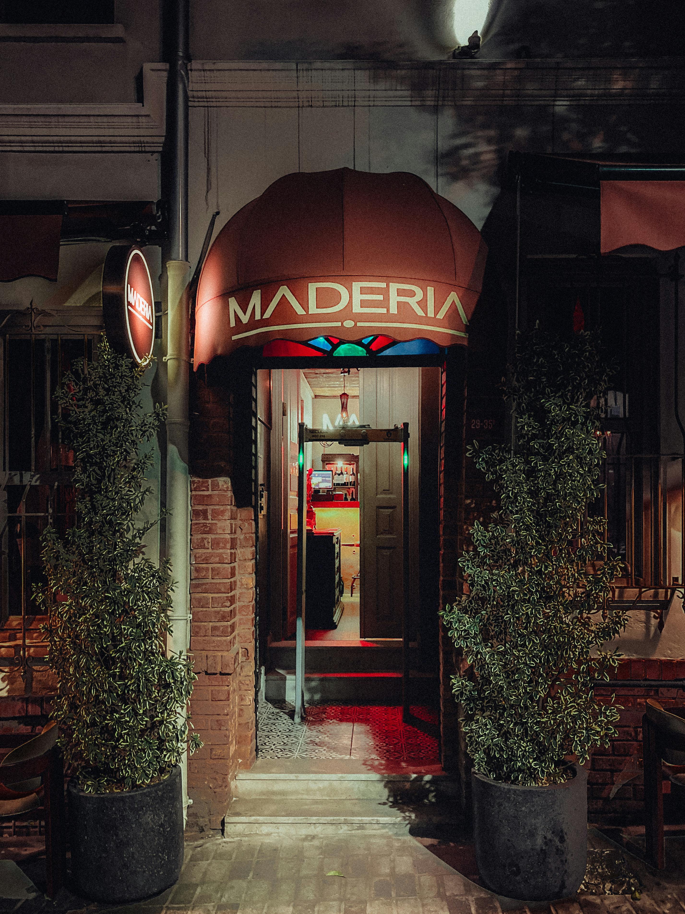 Charming illuminated restaurant entrance at night with ornate signage and foliage.