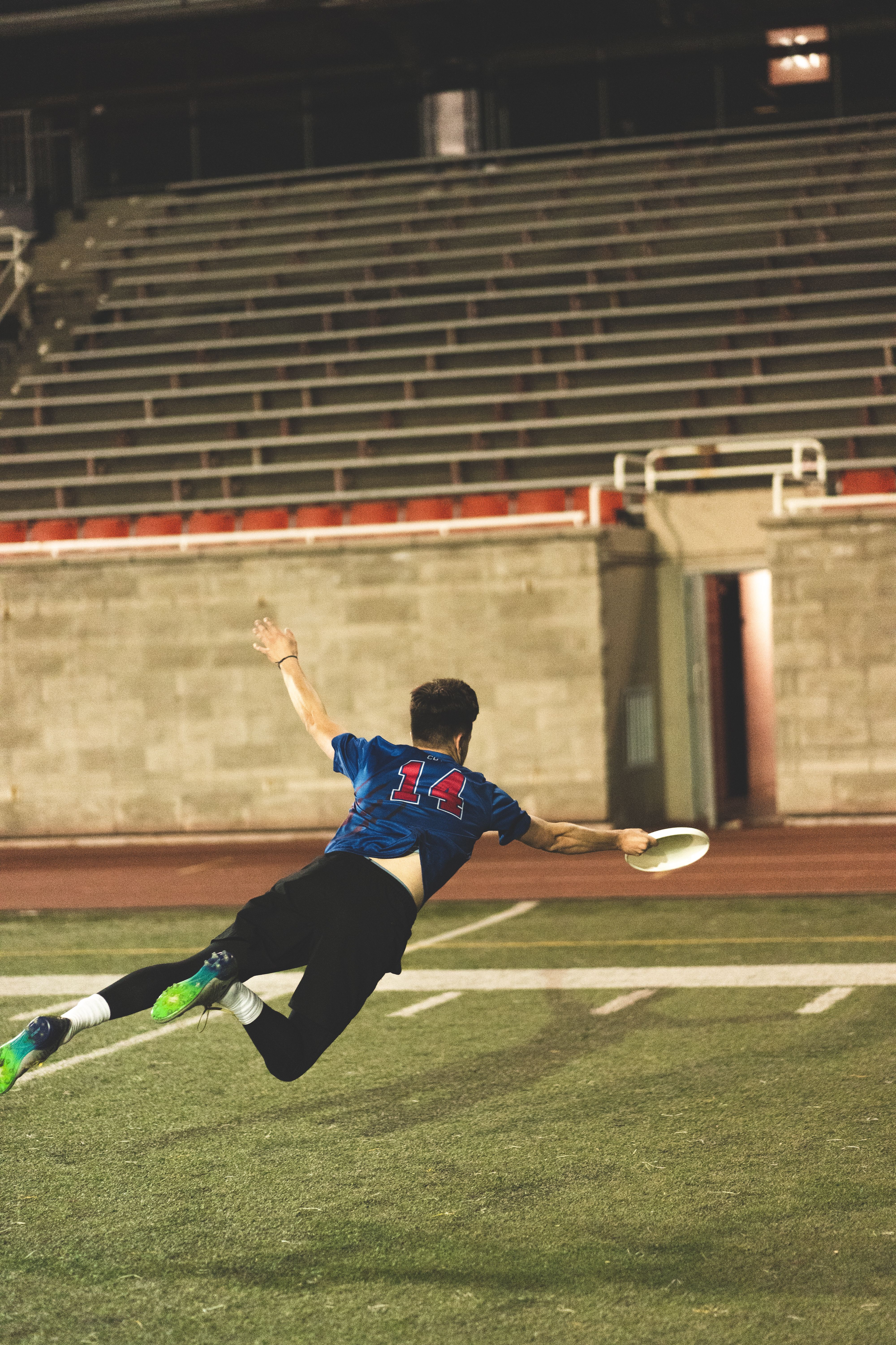 Athlete makes an impressive dive to catch a flying disc on a sports field.