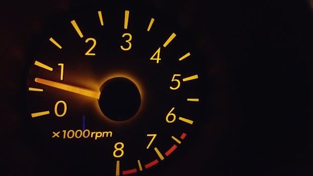 Close-up of a glowing RPM gauge with orange backlight reflecting technology theme.