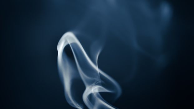 Artistic image of smoke swirling gracefully in contrast to a dark backdrop.
