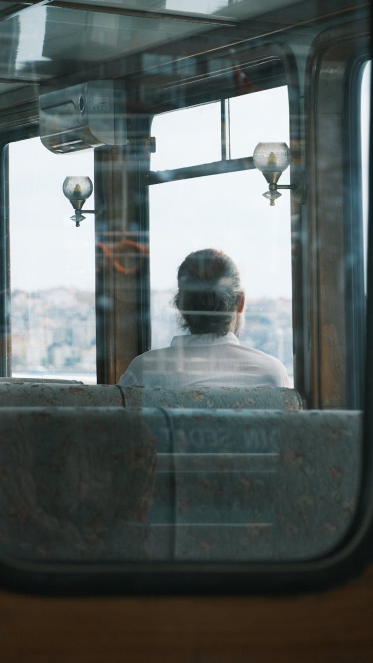 Photo Of A Person Sitting In A Vintage Train Taken Through The Window