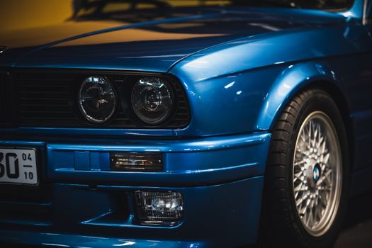Close-up shot of a classic blue car's front featuring headlights and a stylish design.