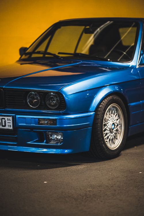 Free A classic blue car parked in a dimly lit indoor setting, showcasing its sleek design and vintage appeal. Stock Photo
