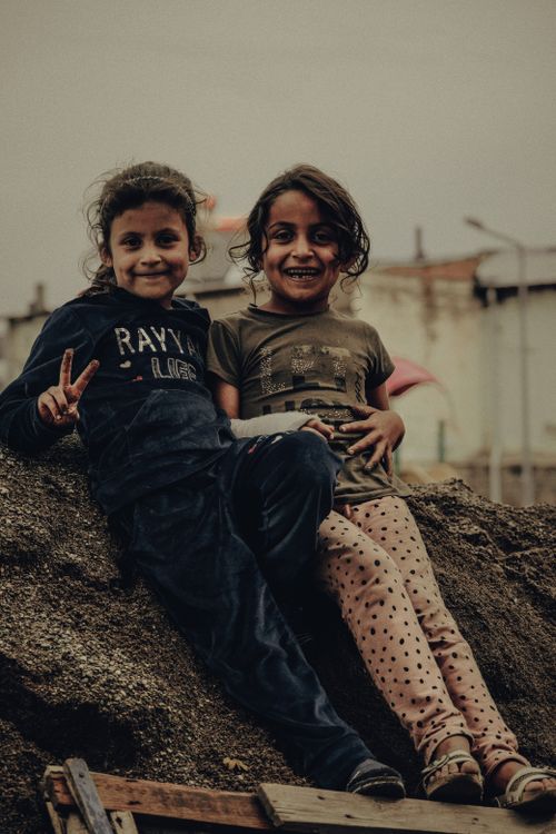 Free Two happy children sitting on a dirt mound, sharing a fun moment outdoors in İncesu, Kayseri. Stock Photo