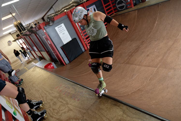 Young Woman In Protective Helmet Making Roller Skating Stunts