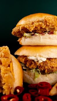 Delicious crispy chicken burgers with fresh chilies on a dark background, perfect fast food indulgence.