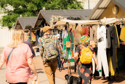 Free A bustling street market scene with people browsing clothes under sunny skies. Stock Photo