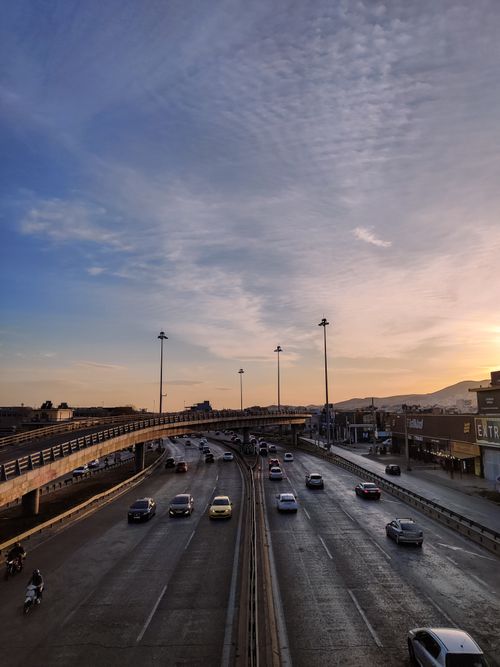 Free Aerial view of a busy highway at sunset with cars and minimal traffic under a vibrant sky. Stock Photo