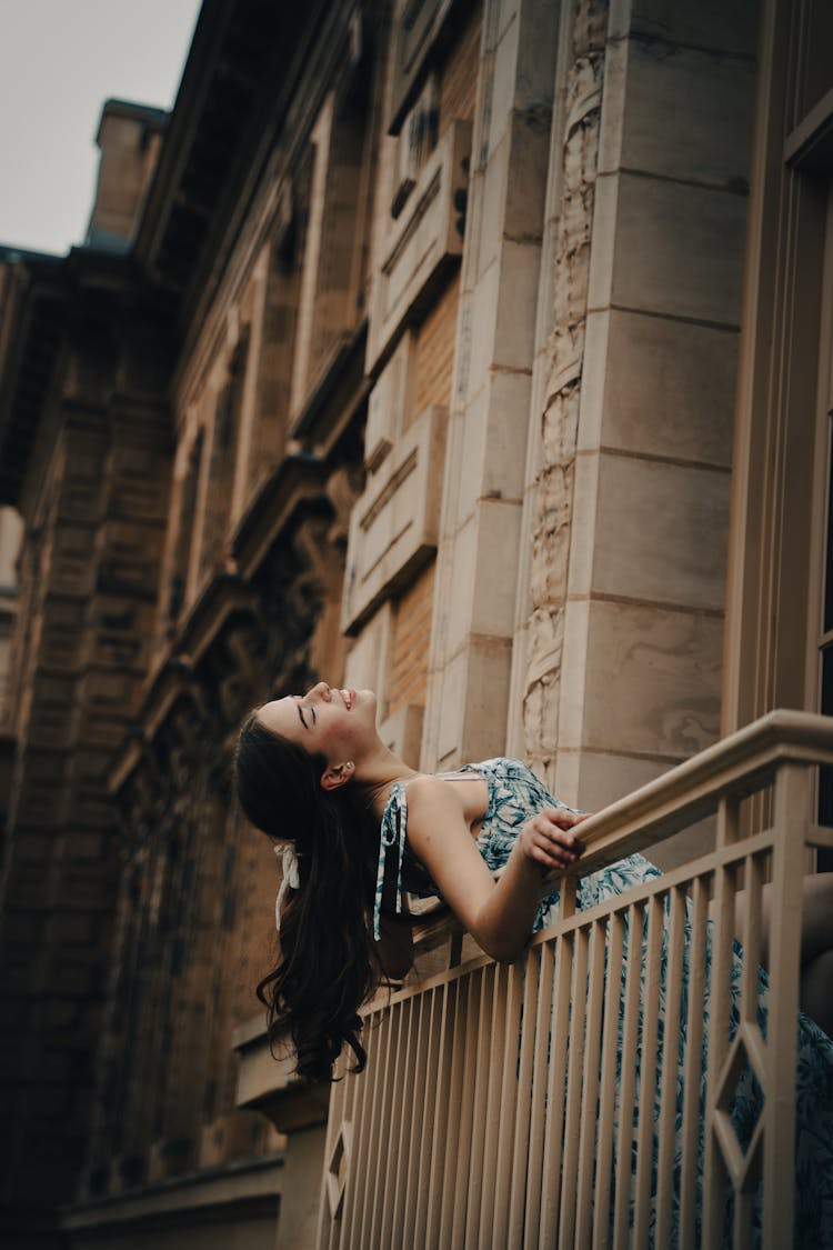 Young Brunette Leaning Out Of A Balcony In A Traditional Building 