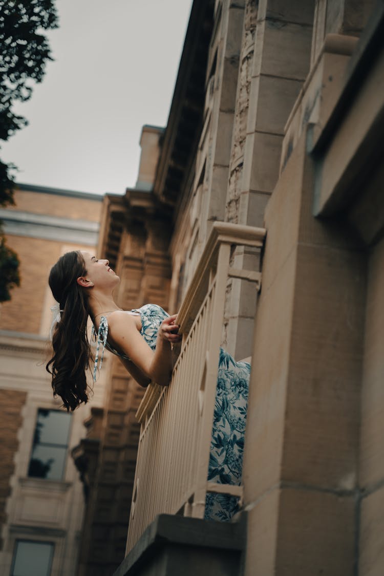 Young Brunette Leaning Out Of A Balcony In A Traditional Building 