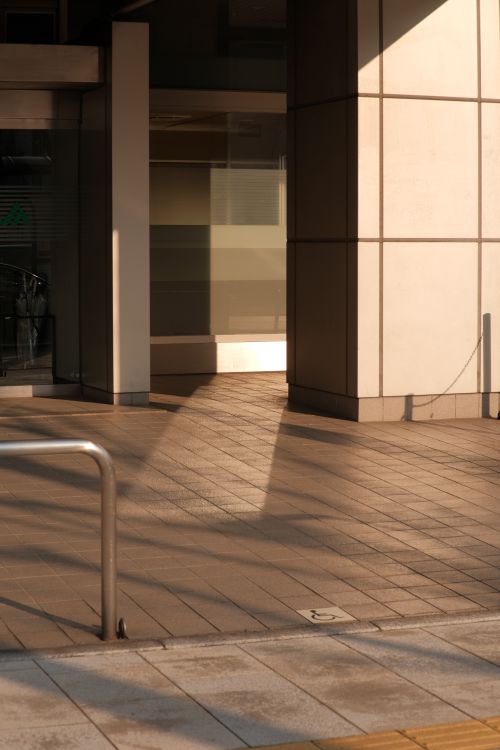 Free A sunlit urban building entrance casting attractive shadows on pavement in the city. Stock Photo