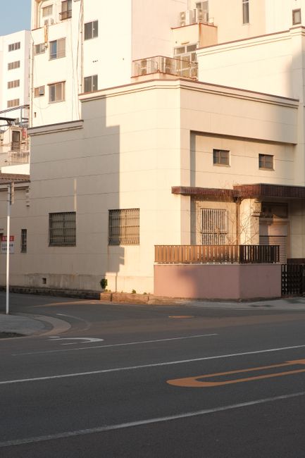 Sunlit corner of modern urban buildings with clean lines and shadows.