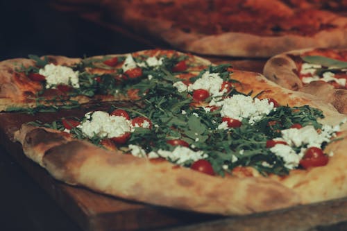 Close-up of a Pizza with Cheese, Cherry Tomatoes and Arugula 