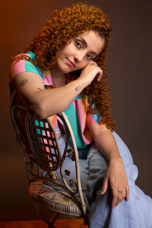 Woman with Long, Curly Hair Sitting on Chair
