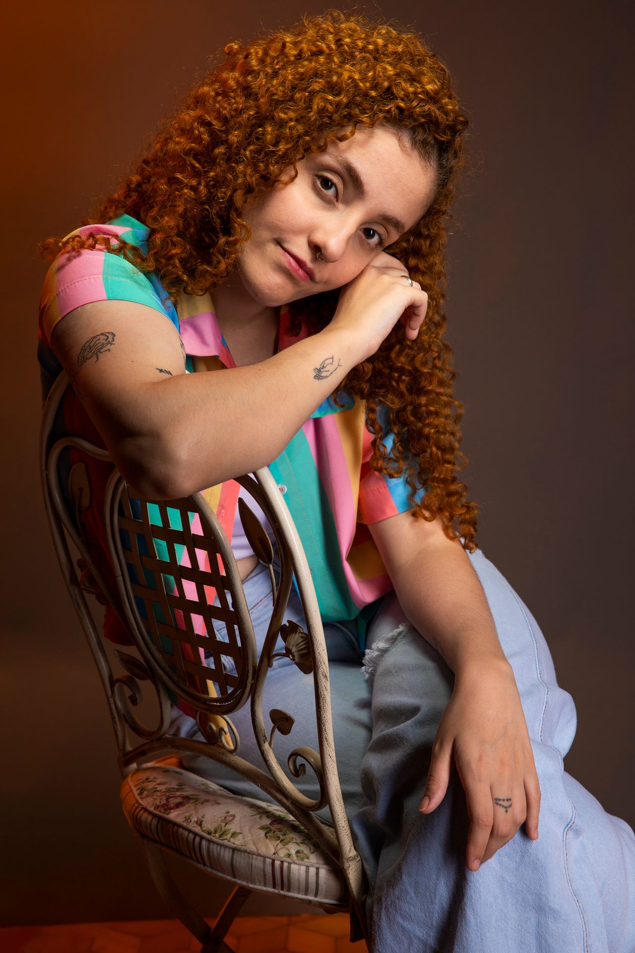 Woman with long layered auburn curls sitting on a chair