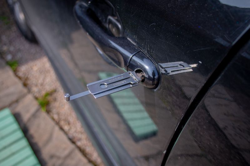 Locksmith tool inserted into a car door lock
