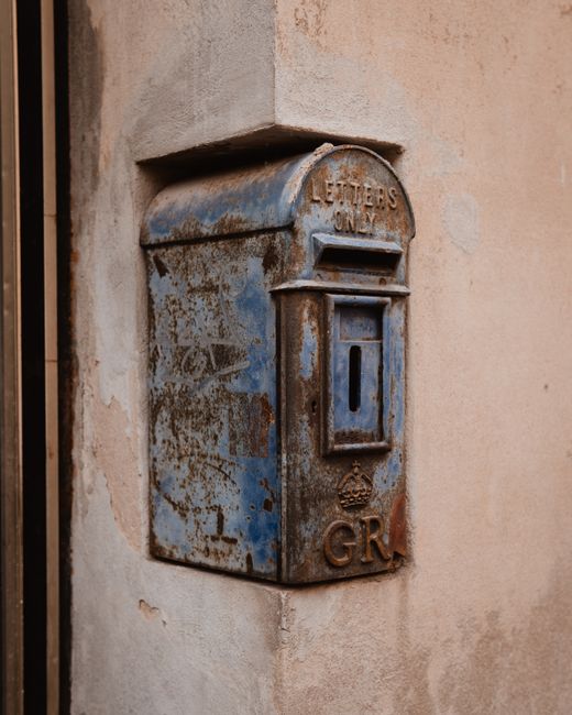 Rusty blue Victorian-era mailbox on a stone corner wall in Nürnberg, Bavaria.