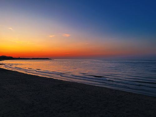 Free Stunning sunset over a tranquil beach, perfect for a serene getaway. Stock Photo