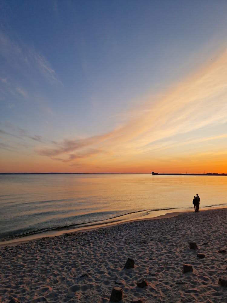 Silhouette Of A People Standing On The Beach At Sunset 