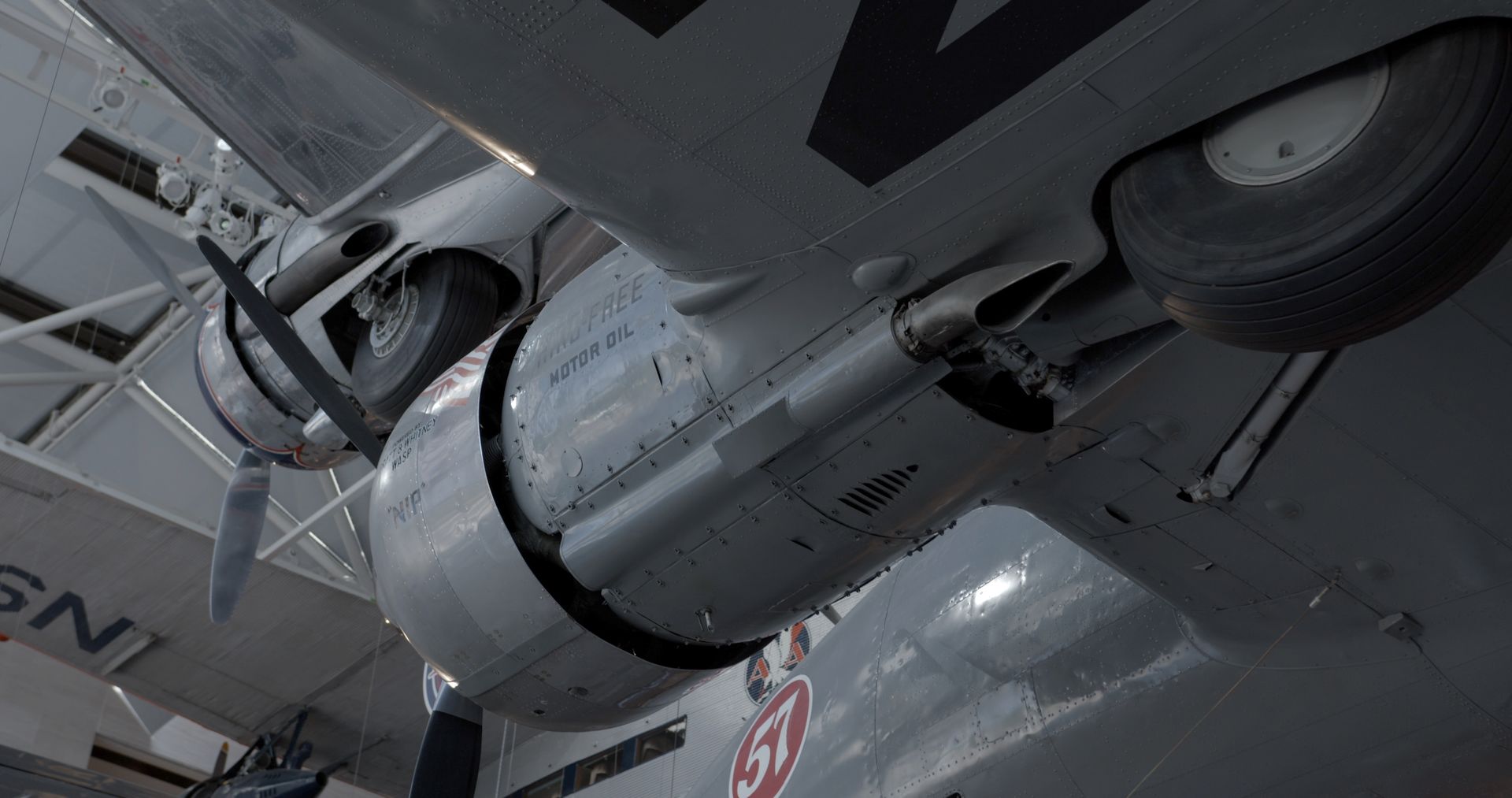 A detailed view of a vintage military aircraft's propeller and wing in an indoor hangar.