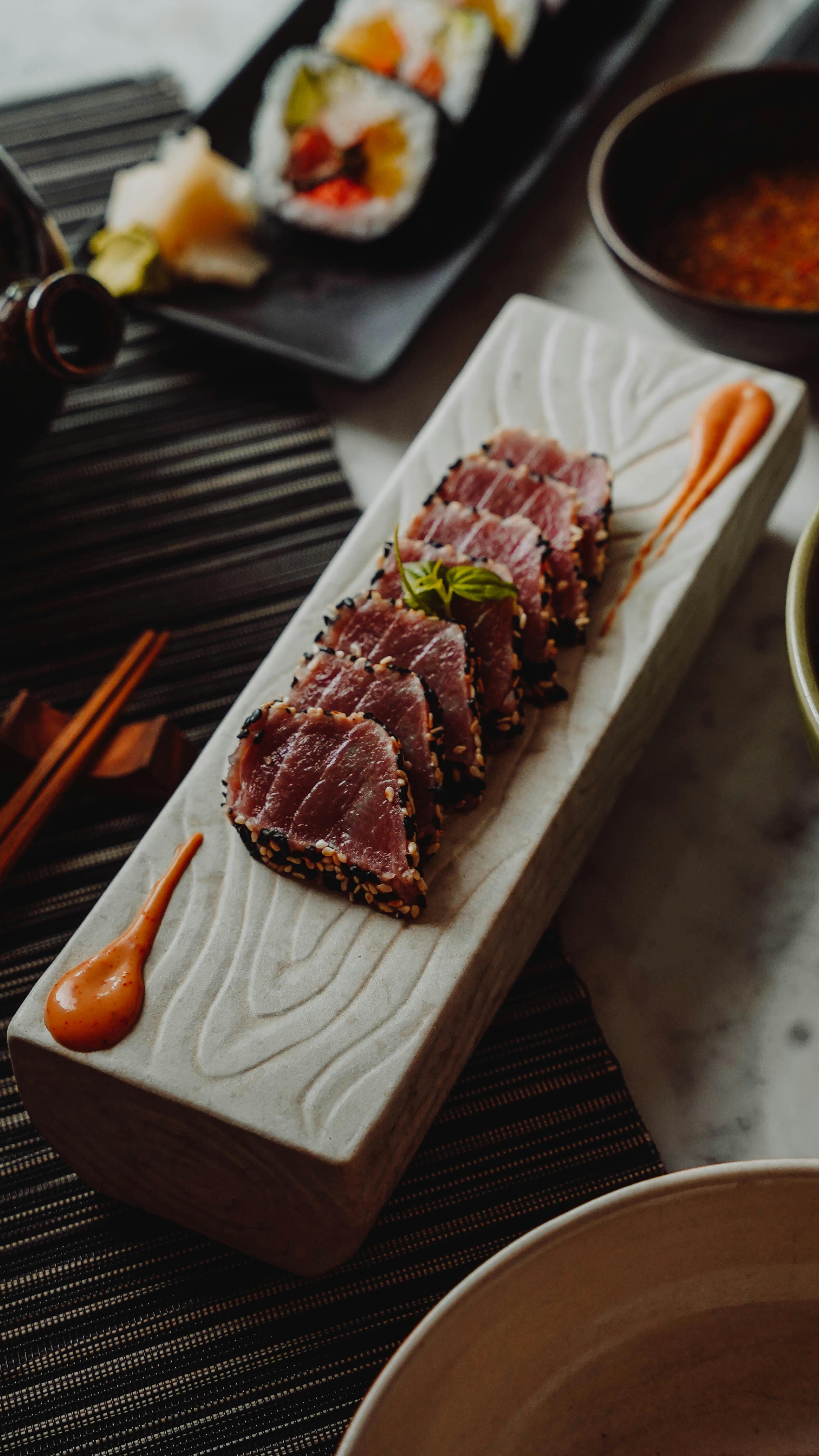 Close-up of perfectly seared tuna slices garnished on a plate with flavorful dressings