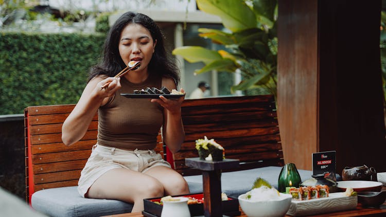 Woman Sitting And Eating Sushi